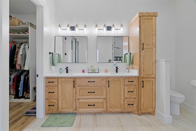 full bathroom with double vanity, a sink, and toilet