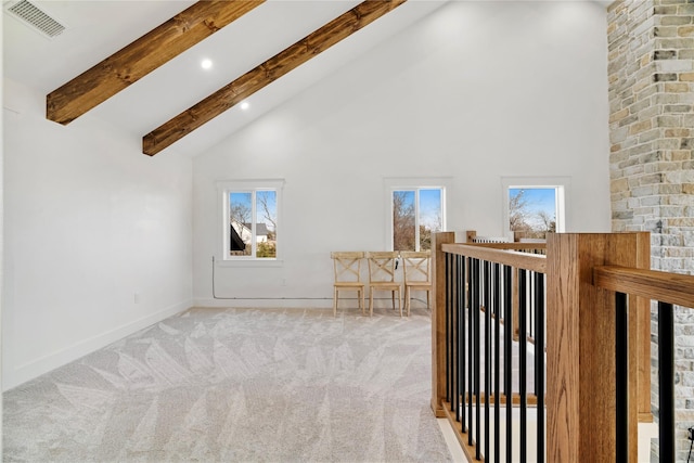 interior space with baseboards, visible vents, light colored carpet, beamed ceiling, and high vaulted ceiling