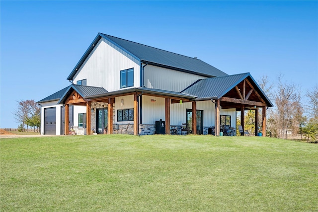 rear view of property featuring a garage, metal roof, and a lawn