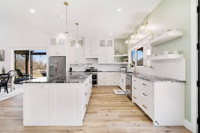 kitchen with glass insert cabinets, appliances with stainless steel finishes, open shelves, and white cabinets