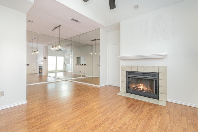 unfurnished living room with a fireplace, visible vents, a ceiling fan, light wood-type flooring, and baseboards