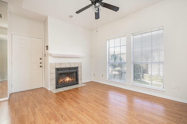 unfurnished living room with light wood finished floors, visible vents, baseboards, a ceiling fan, and a fireplace