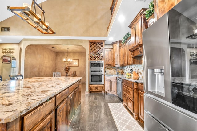 kitchen with stainless steel appliances, hanging light fixtures, brown cabinetry, and visible vents