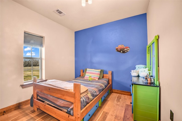 bedroom featuring baseboards, visible vents, and light wood finished floors