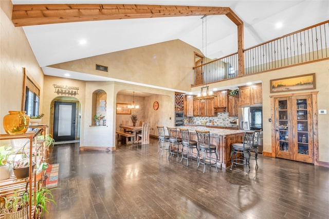 kitchen with visible vents, dark wood finished floors, arched walkways, brown cabinets, and a kitchen breakfast bar