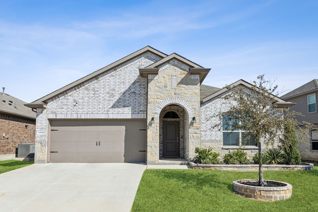 french country home featuring brick siding, concrete driveway, a front yard, a garage, and stone siding