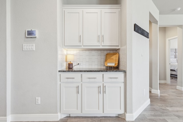 bar featuring tasteful backsplash, light wood-type flooring, and baseboards