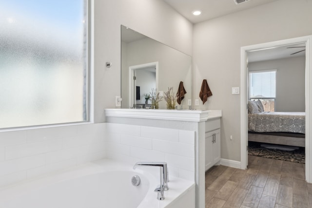 bathroom featuring baseboards, ensuite bath, wood finished floors, vanity, and a bath