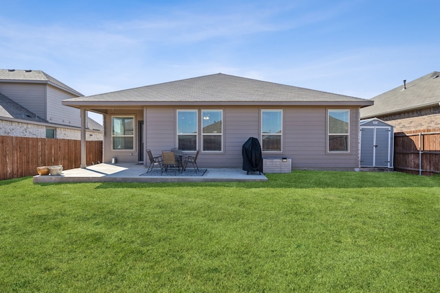 back of house with an outbuilding, a fenced backyard, a lawn, a storage unit, and a patio area