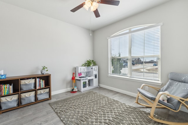 living area featuring light wood-style floors, ceiling fan, and baseboards