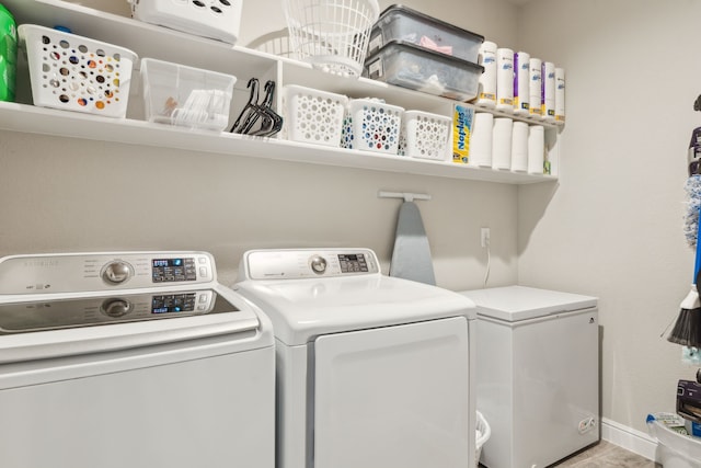 washroom with laundry area, separate washer and dryer, and baseboards