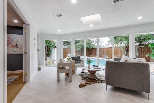 living room featuring a skylight, visible vents, baseboards, and recessed lighting