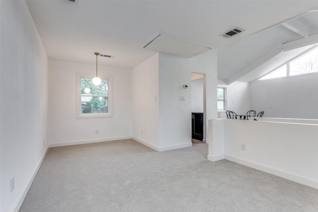 unfurnished room with attic access, a wealth of natural light, visible vents, and light carpet