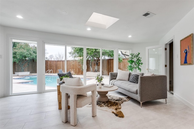 living room featuring baseboards, a skylight, visible vents, and recessed lighting