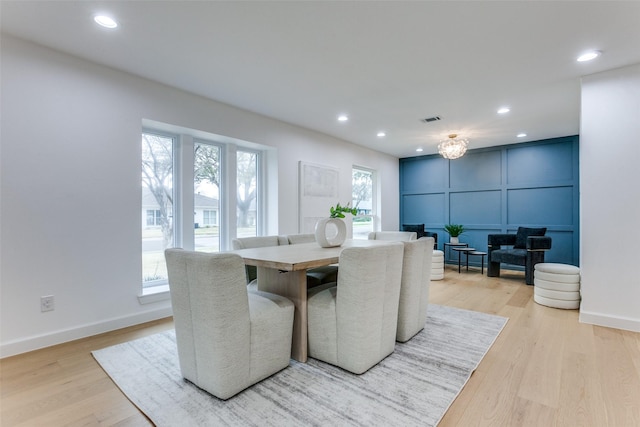 dining room with light wood-style flooring, visible vents, a decorative wall, and recessed lighting