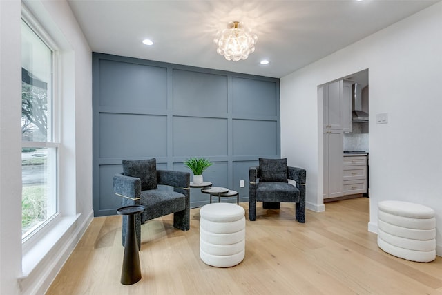 sitting room featuring a chandelier, a decorative wall, and light wood-style flooring