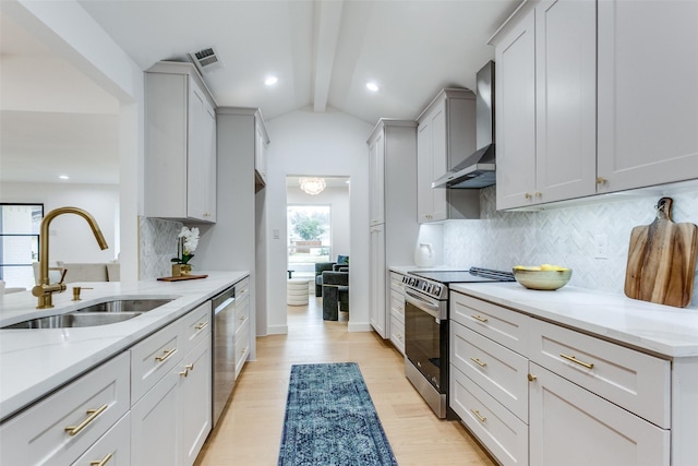 kitchen with stainless steel appliances, a sink, visible vents, light wood-style floors, and wall chimney range hood