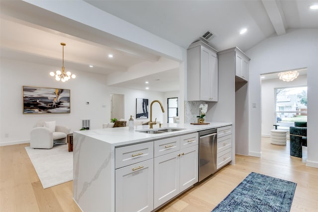 kitchen with a sink, visible vents, stainless steel dishwasher, light stone countertops, and an inviting chandelier