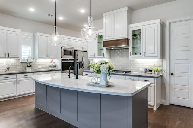 kitchen featuring appliances with stainless steel finishes, dark wood-type flooring, glass insert cabinets, and custom exhaust hood