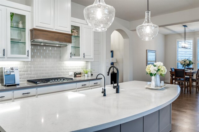 kitchen featuring dark wood-style floors, custom range hood, stainless steel gas cooktop, and white cabinets