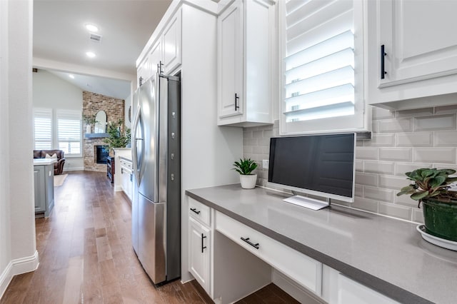 kitchen featuring vaulted ceiling, wood finished floors, freestanding refrigerator, and white cabinetry