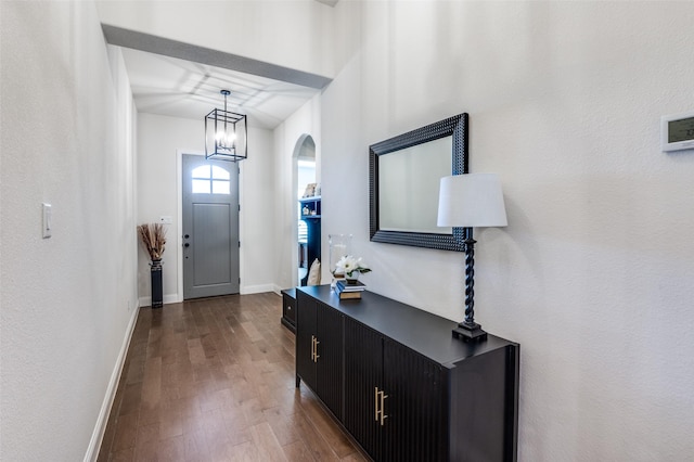 entrance foyer featuring dark wood-style floors, baseboards, and an inviting chandelier