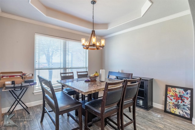 dining area featuring crown molding, baseboards, a raised ceiling, and wood finished floors