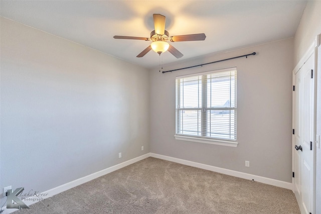 carpeted spare room featuring baseboards and a ceiling fan