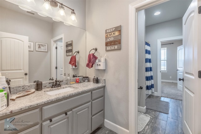 bathroom featuring wood finish floors, visible vents, vanity, and baseboards