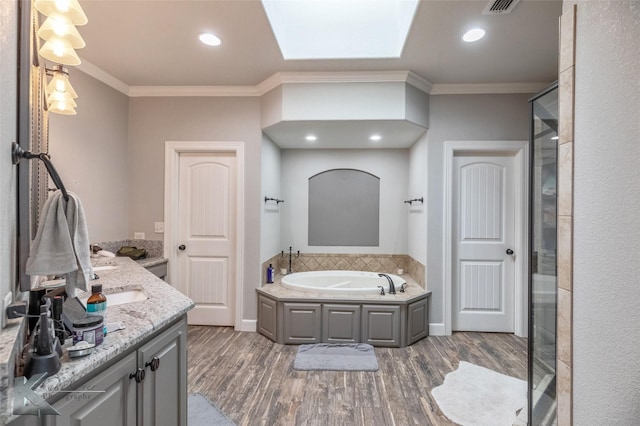 full bathroom with a garden tub, a skylight, wood finished floors, double vanity, and crown molding