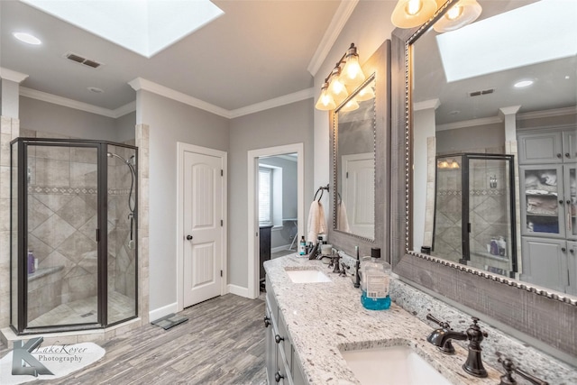 full bath featuring a stall shower, a skylight, a sink, and baseboards