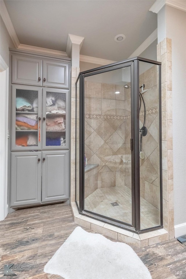 bathroom featuring ornamental molding, a stall shower, and wood finished floors