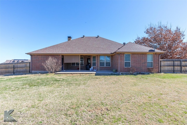 rear view of house featuring a fenced backyard, a lawn, a patio, and brick siding