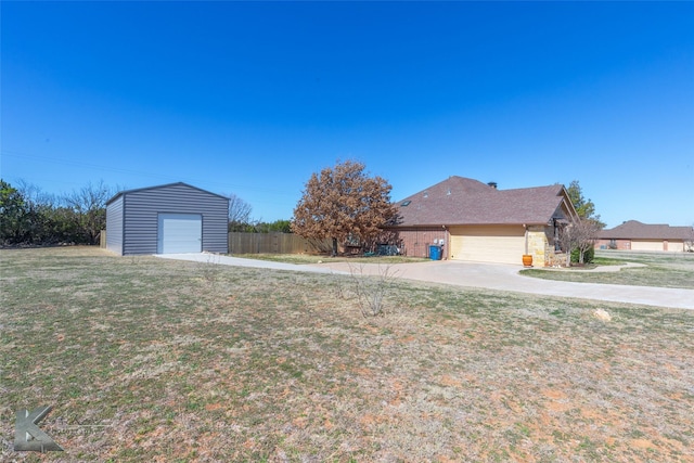 view of yard featuring a garage, fence, and an outbuilding