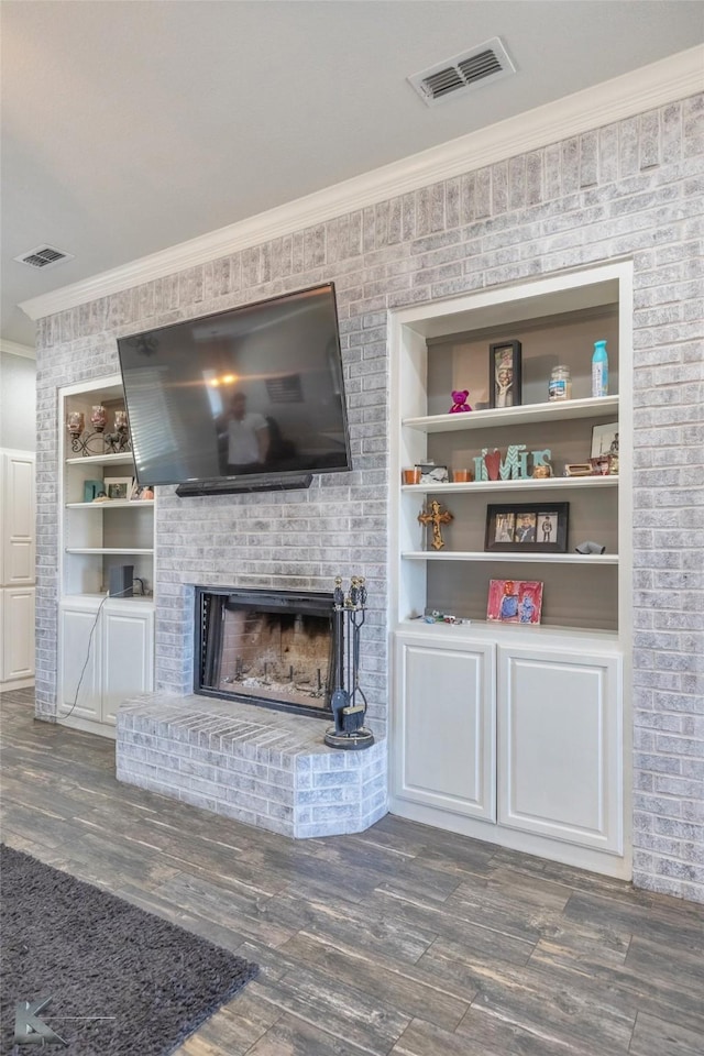 unfurnished living room featuring a brick fireplace, visible vents, dark wood-type flooring, and crown molding