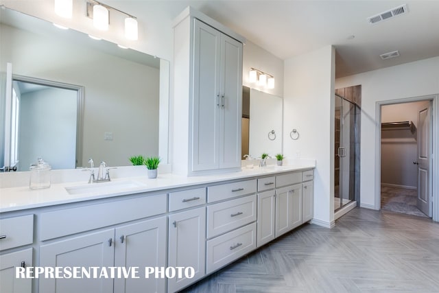 full bathroom with a sink, visible vents, double vanity, a stall shower, and a walk in closet