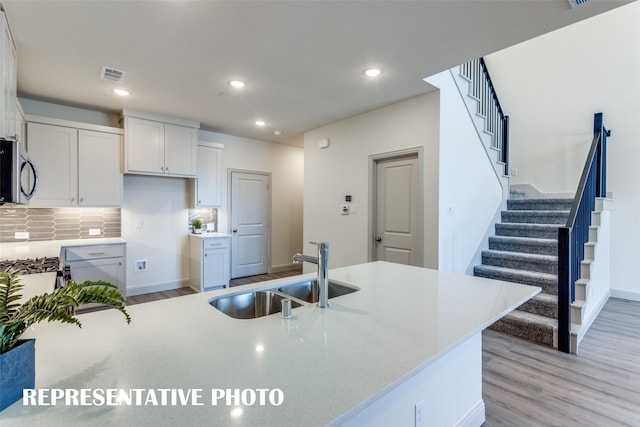 kitchen featuring a sink, visible vents, white cabinetry, light countertops, and stainless steel microwave