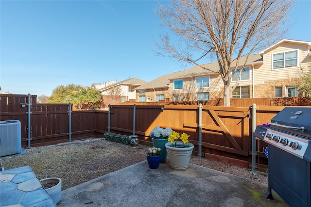 view of yard featuring cooling unit, a gate, a fenced backyard, and a patio