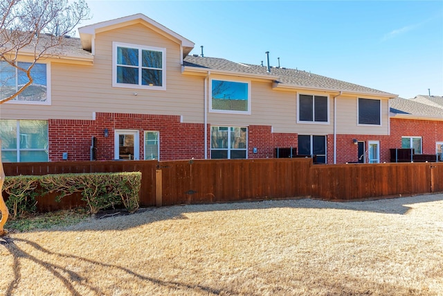 back of house featuring brick siding and fence private yard