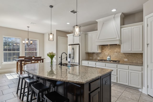 kitchen featuring premium range hood, a center island with sink, appliances with stainless steel finishes, and white cabinets