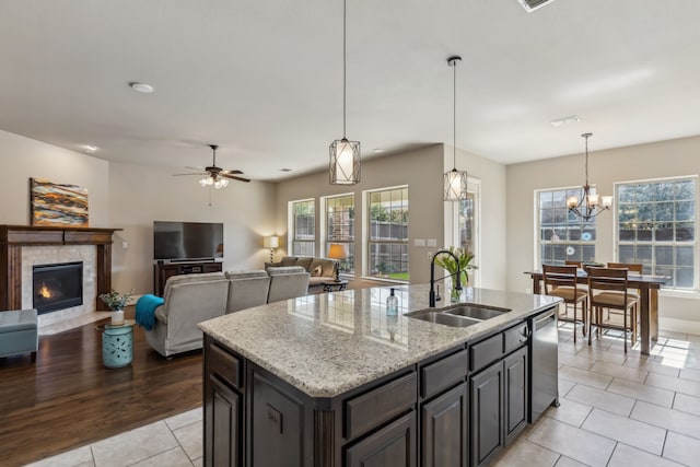 kitchen with dishwasher, a center island with sink, pendant lighting, and a sink