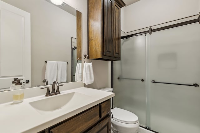 full bathroom with toilet, a shower with door, and vanity