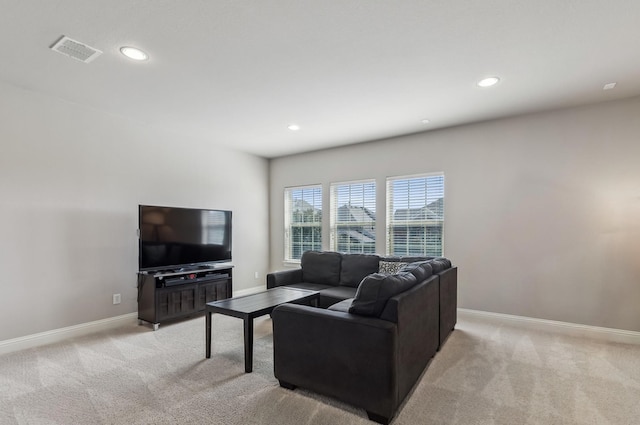 living area featuring baseboards, visible vents, and light colored carpet