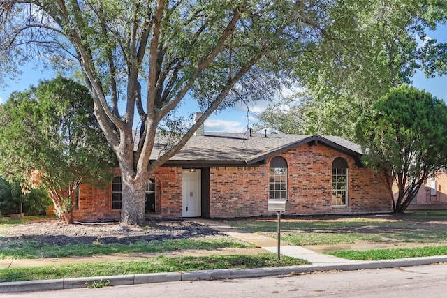 single story home featuring roof with shingles, brick siding, and a chimney