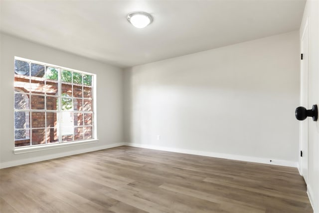 spare room featuring baseboards and wood finished floors