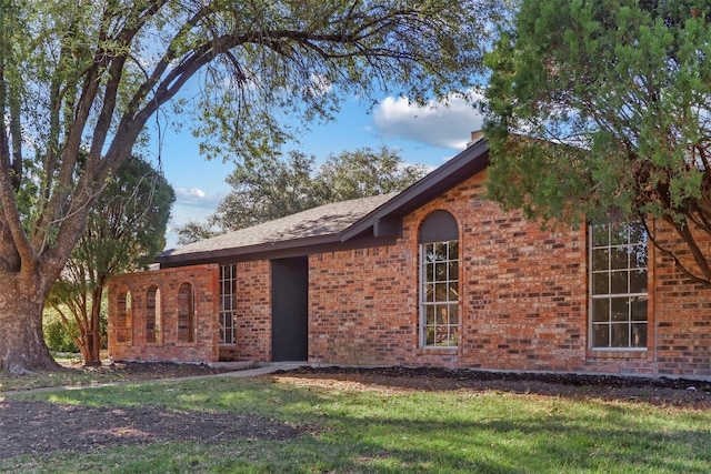 view of front facade with brick siding and a front lawn