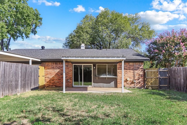 rear view of house featuring a yard, a gate, brick siding, and a patio