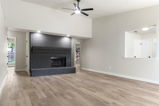 unfurnished living room featuring visible vents, baseboards, a ceiling fan, light wood-style floors, and a brick fireplace