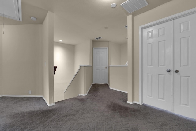 hall with dark colored carpet, visible vents, attic access, an upstairs landing, and baseboards