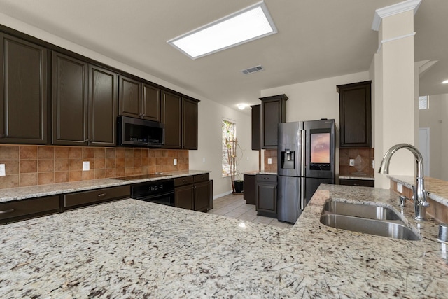 kitchen with stainless steel appliances, a sink, visible vents, dark brown cabinets, and decorative backsplash